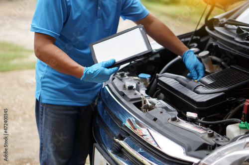 Mechanic is checking car engine, use smart tablet to record and diagnose the problems of engine Concept : using technology to manage car engine. Car service and maintenance. 