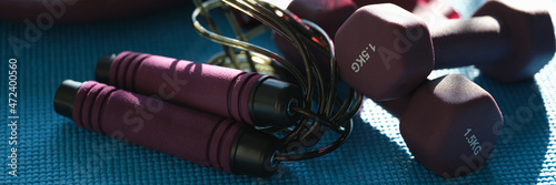 Sports accessories dumbbell skipping rope lie on mat closeup