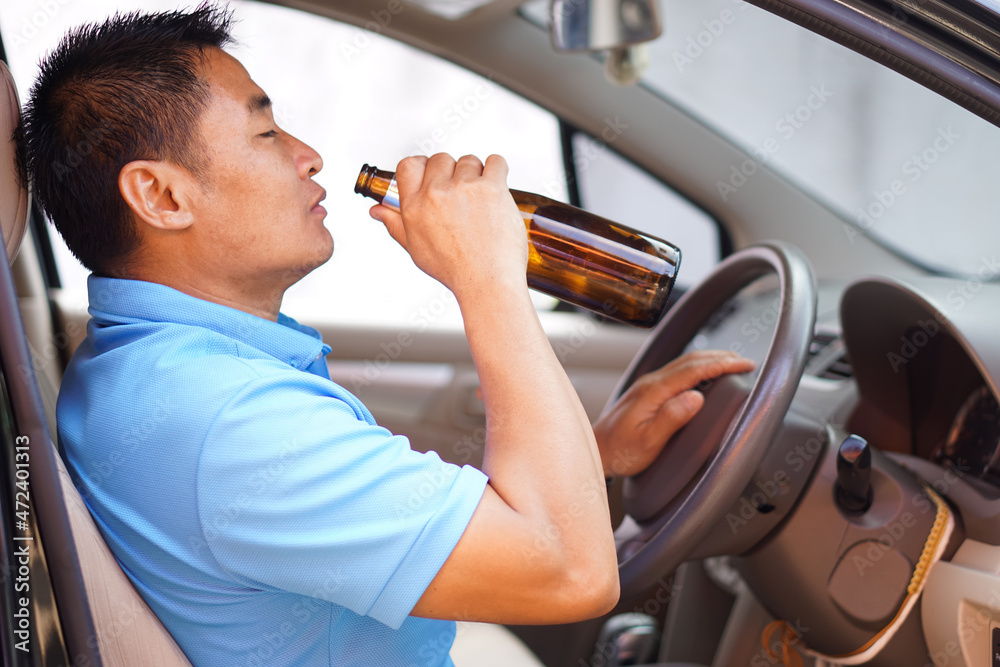 Drunk man is drinking beer from bottle in car. Concept Campaign for