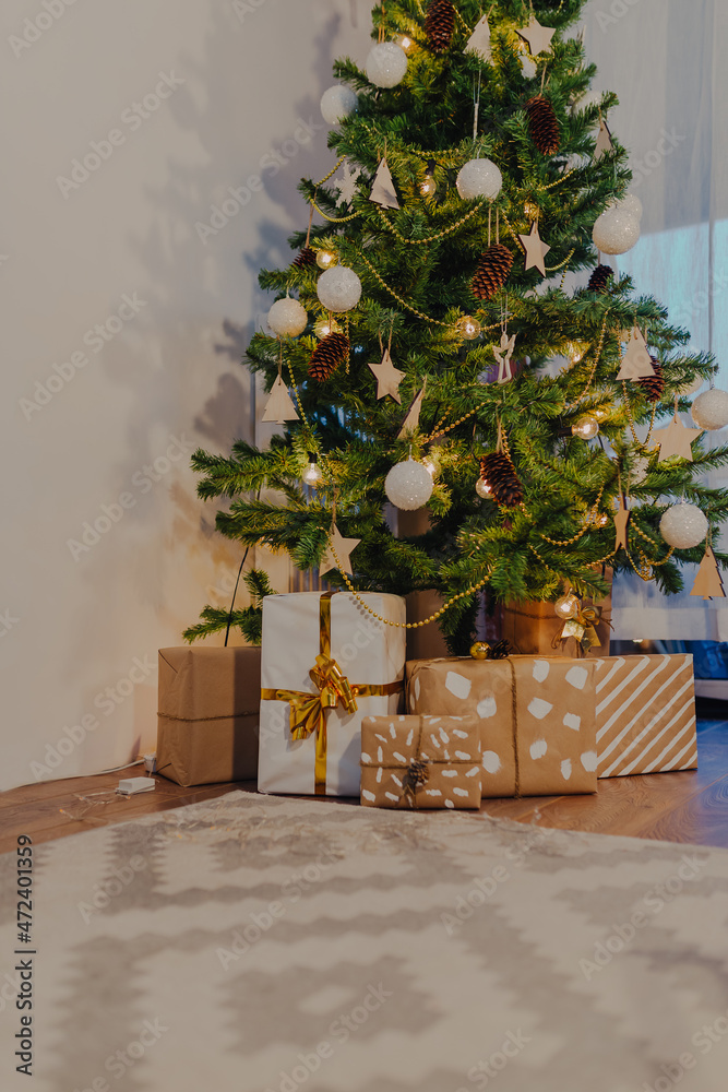 Obraz premium Christmas gifts wrapped in kraft paper under christmas tree.