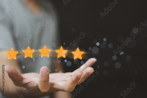 Businessman holding virtual five stars for customer feedback rating and evaluation concept.