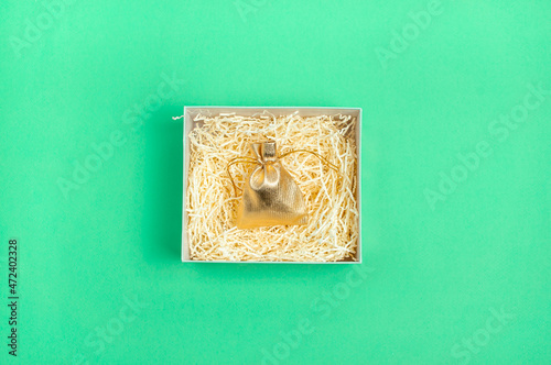 Open box with stuff on bright green background with yellow paper stuff in empty box with little golden bag. Minimalist composition. Copy space. photo