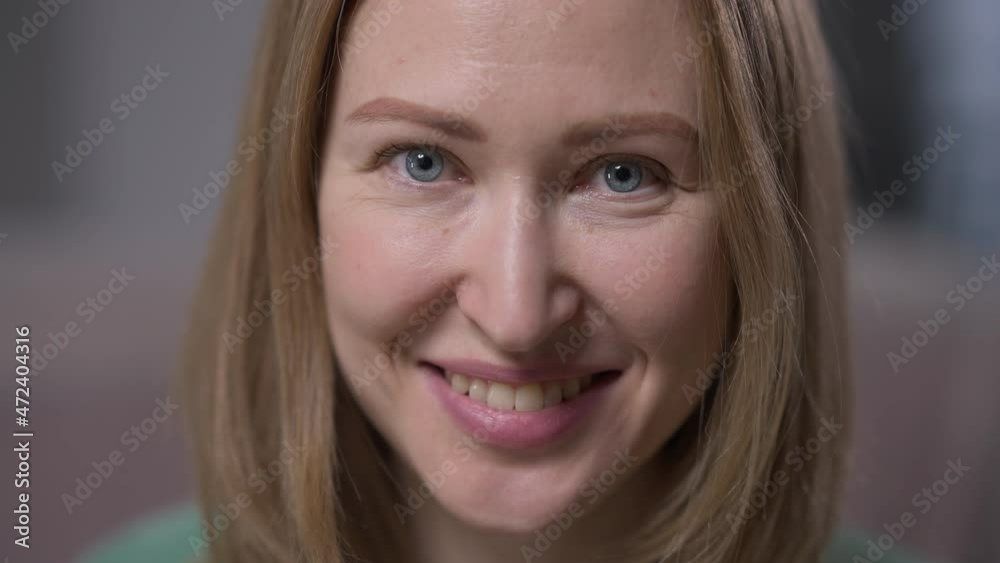 Headshot portrait happy confident young woman with grey eyes looking at camera smiling. Close-up front view Caucasian millennial beautiful lady posing indoors in slow motion Headshot portrait happy confident young woman with grey eyes looking at camera smiling. Close-up front view Caucasian millennial beautiful lady posing indoors in slow motion