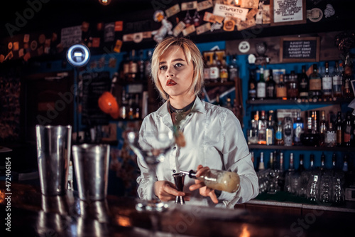 Girl barman formulates a cocktail on the taproom