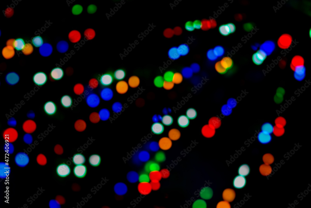 Multicolored bokeh of Christmas garlands on a Christmas tree at night on street Christmas Eve and New Years. Bright flashes of colored lights, bokeh texture. Festive colorful background. 