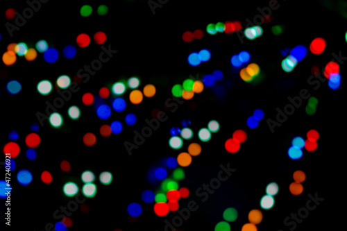 Multicolored bokeh of Christmas garlands on a Christmas tree at night on street Christmas Eve and New Years. Bright flashes of colored lights, bokeh texture. Festive colorful background. 