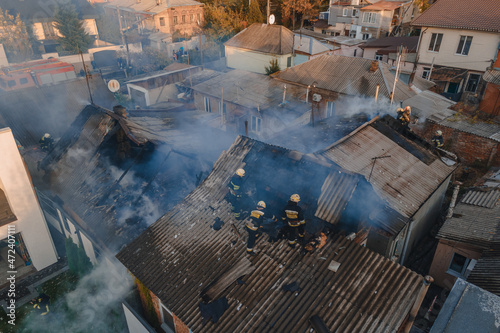  Severe fire in a private house. the roof is on fire. Thick smoke in the sky. Photo from the drone. Rescuers put out the fire.