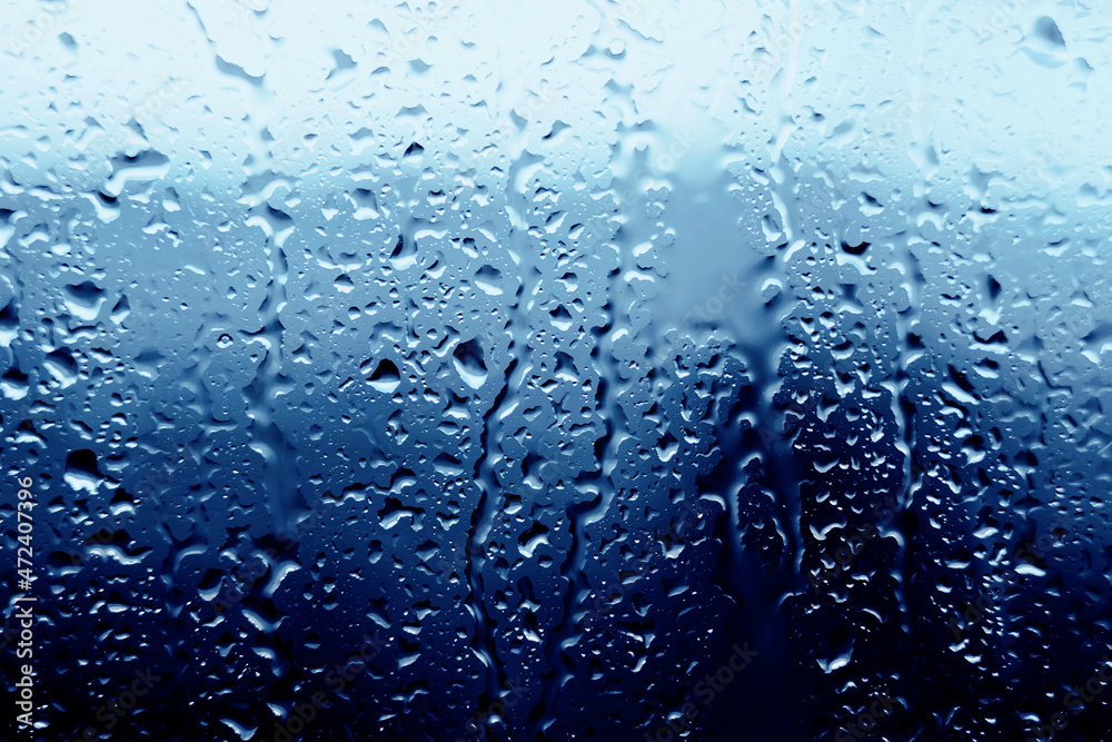 Raindrops fall on the transparent window glass during a downpour on a cold autumn day. Cloudy wet sad weather. Water. Melancholy.