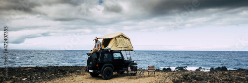 Foto Banner travel header with man sitting on the roof of the car with camping tent h