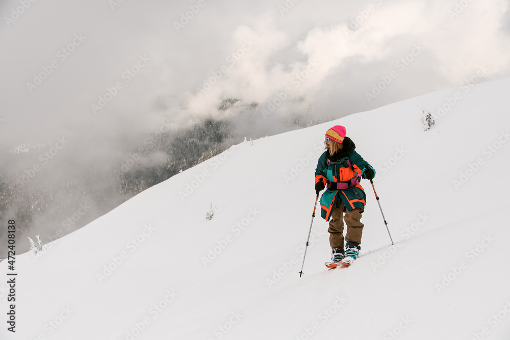 man skier with trekking poles on snowy hill trail with cloudy sky in the background. man skier with trekking poles on snowy hill trail with cloudy sky in the background.