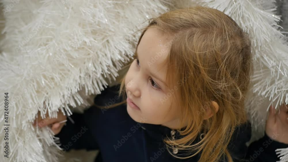 portrait. slow motion Cute preschool girl playing hide and seek in Christmas tinsel. Completely hides in tinsel and exits. Store of New Year's decor and gifts for Christmas portrait. slow motion Cute preschool girl playing hide and seek in Christmas tinsel. Completely hides in tinsel and exits. Store of New Year's decor and gifts for Christmas