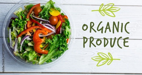 Overhead view of organic produce symbol by fresh salad in bowl on wooden table