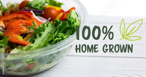 Close-up of 100 percent home grown text by fresh salad bowl on wooden table