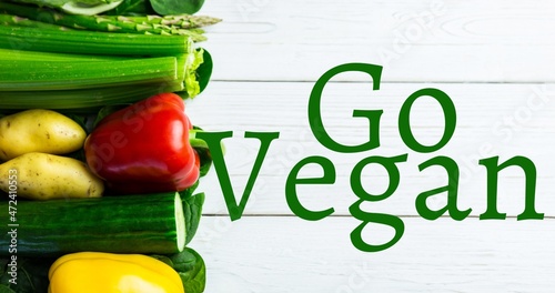 Directly above view of go vegan text by fresh vegetables on wooden table