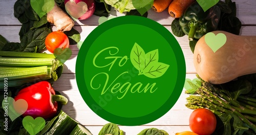 Directly above view of go vegan symbol text over fresh vegetables arranged on table
