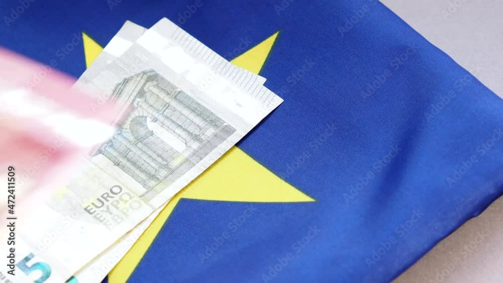 Person putting currency 5, 10 and 20 euros on flag of European Union, business concept video