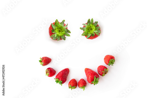 juicy, ripe strawberries on a white background. Strawberry in the shape of a smiling face with fangs. funny or scary face made of berries. isolated. flat lay.