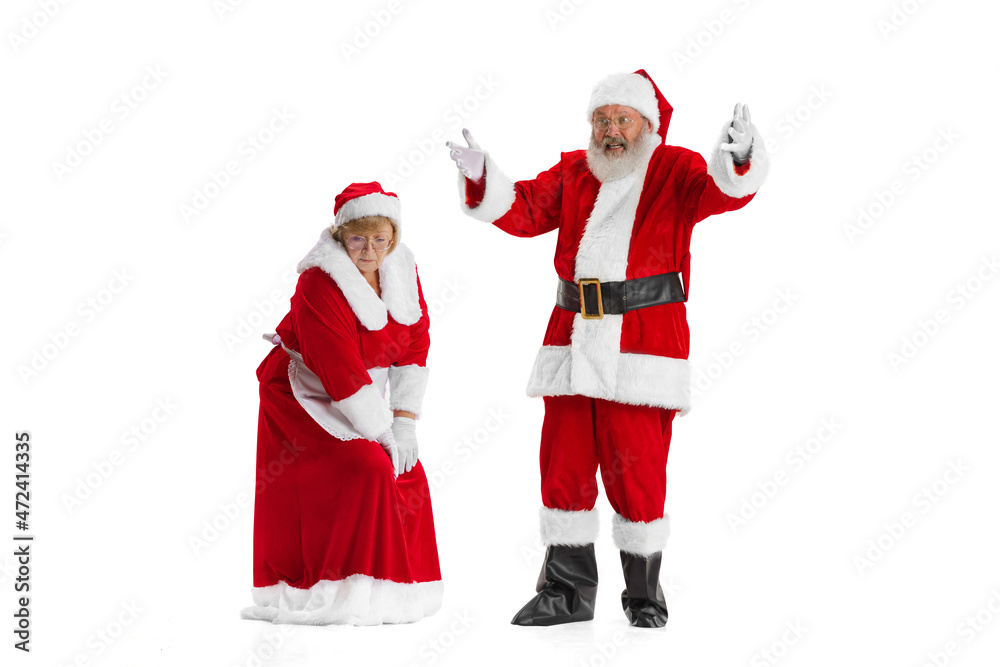 Excited senior man and beautiful woman, Santa Claus and missis Claus in traditional New Year costume isolated on white background. Excited senior man and beautiful woman, Santa Claus and missis Claus in traditional New Year costume isolated on white background.