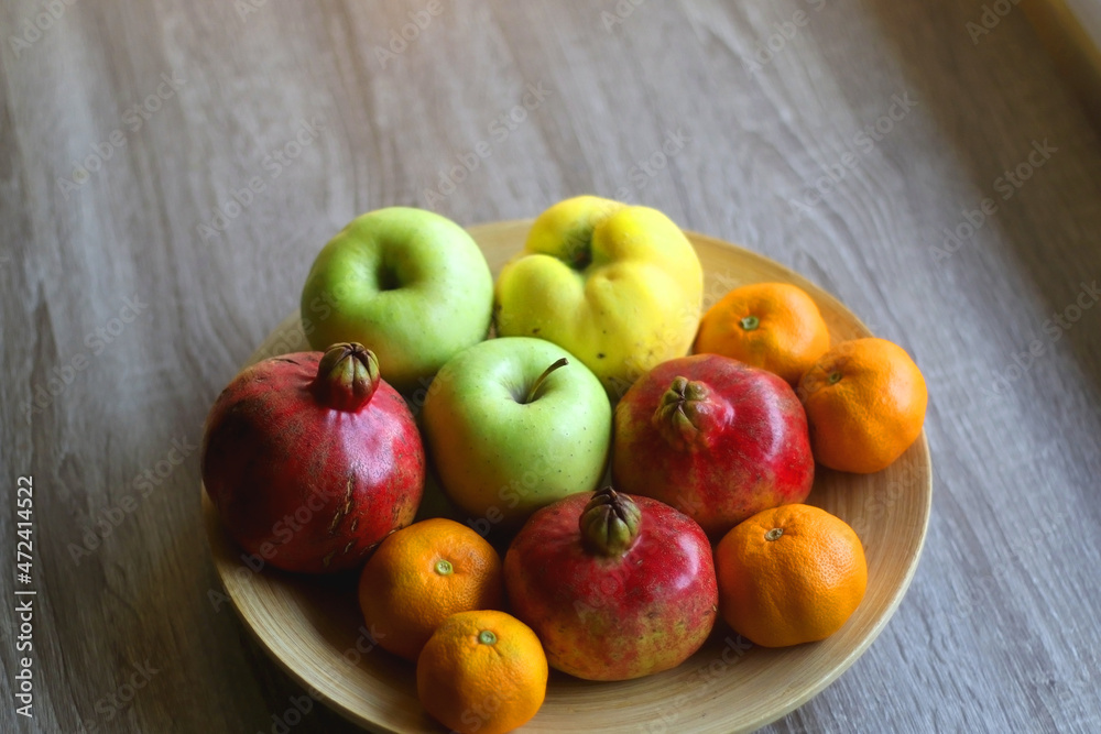 Wooden bowl filled with various seasonal fruit on a table. Selective focus. Wooden bowl filled with various seasonal fruit on a table. Selective focus.
