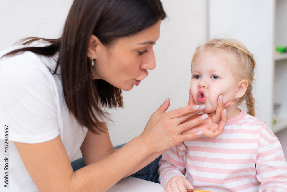 Woman speech therapist helps cute girl to learn correct pronunciation and literate speech Woman speech therapist helps cute girl to learn correct pronunciation and literate speech
