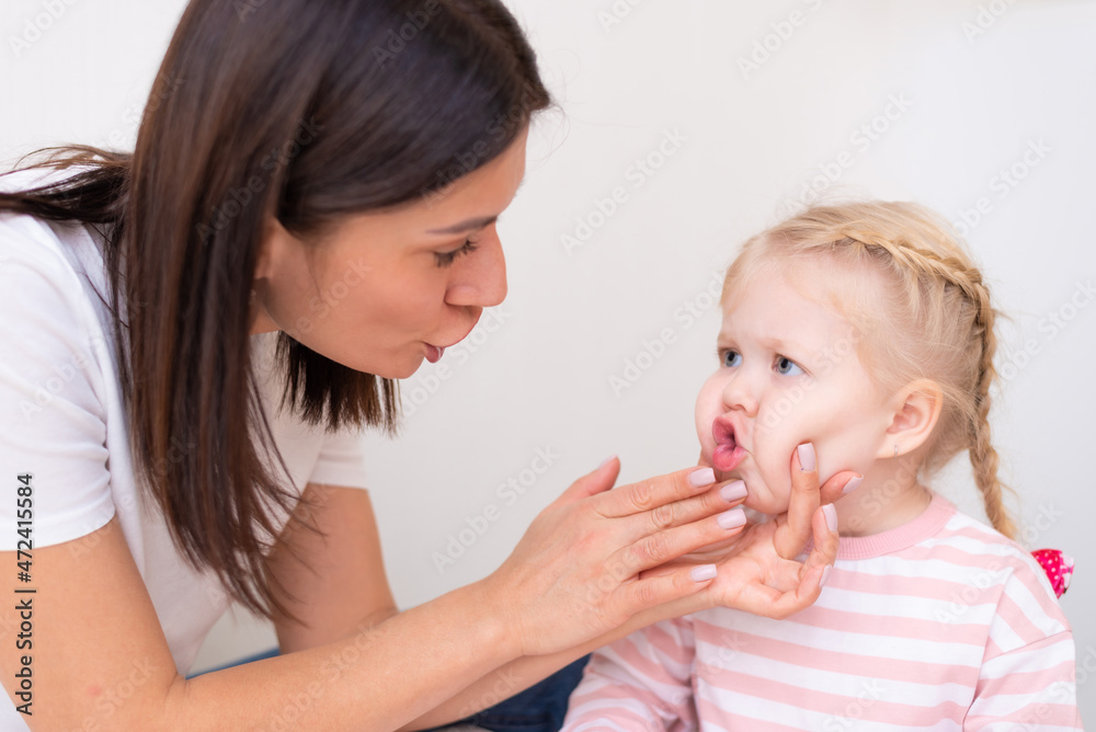 Woman speech therapist helps cute girl to learn correct pronunciation and literate speech Woman speech therapist helps cute girl to learn correct pronunciation and literate speech