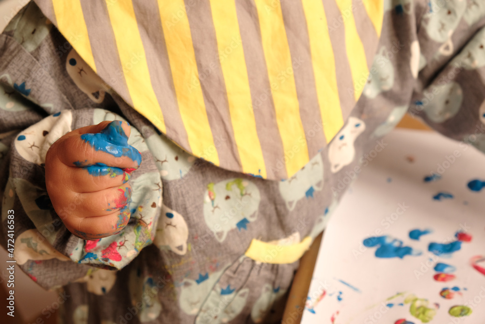 Early childhood activity: close-up of a child’s hand with fingers covered with paint after finger painting and a drawing