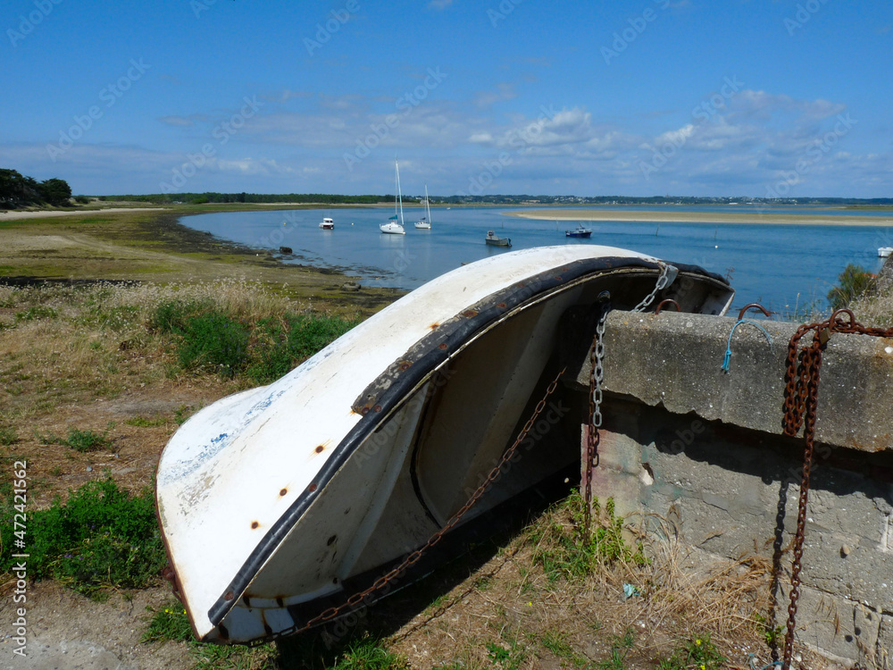 Boat tipped on the dry with metal chains and harbor in the background, France Boat tipped on the dry with metal chains and harbor in the background, France
