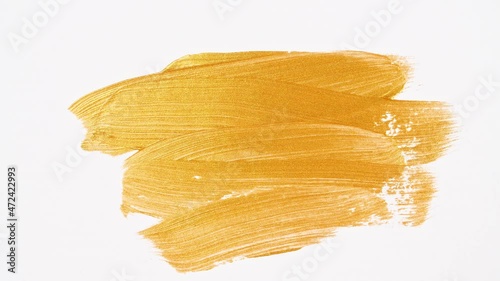 Abstract brushstrokes of gold paint brush applied isolated on a white background. Gold paint smear texture. Golden sparkling textured artistic illustration. Smears of cosmetics. High quality 4k  photo