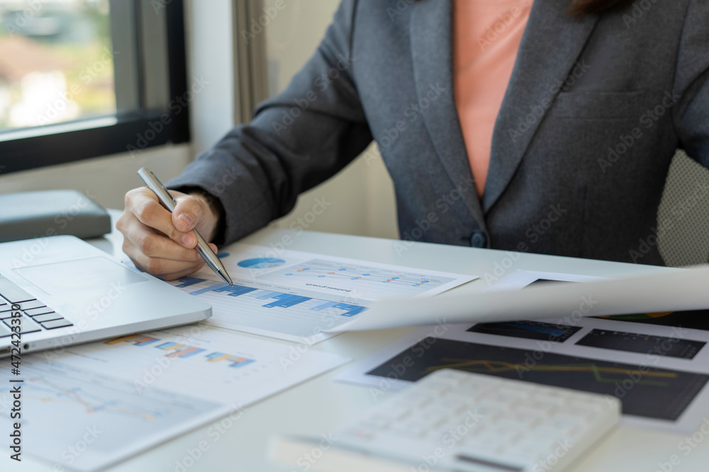 Close up of businesswoman or accountant using a calculator to calculate, calculate business data, accounting document in the office table, working at office, business and finance concept Close up of businesswoman or accountant using a calculator to calculate, calculate business data, accounting document in the office table, working at office, business and finance concept