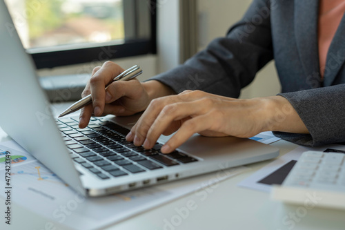 businesswoman is typing on the keyboard of laptop for check electronic mail, preparation of presentation in a meeting, get information for shopping online or operation of internet banking