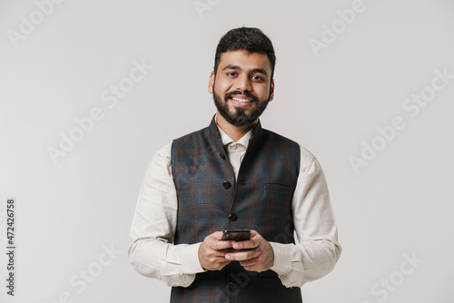 Bearded south asian man wearing vest using cellphone © Drobot Dean
