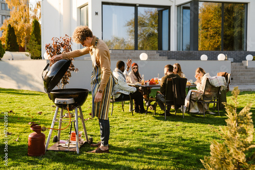 Fotografie Multiracial friends talking and laughing during barbeque in garden