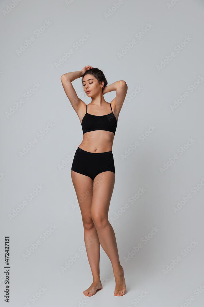 Full-length portrait of young beautiful slim girl in underwear posing isolated over gray studio background. Natural beauty concept. Full-length portrait of young beautiful slim girl in underwear posing isolated over gray studio background. Natural beauty concept.