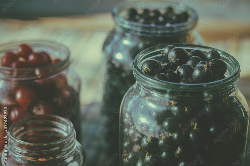 Fresh berries from a private garden in glass jars on a checkered blanket. Harvest of blackcurrant berries, cherries and strawberries. Selective focus Fresh berries from a private garden in glass jars on a checkered blanket. Harvest of blackcurrant berries, cherries and strawberries. Selective focus