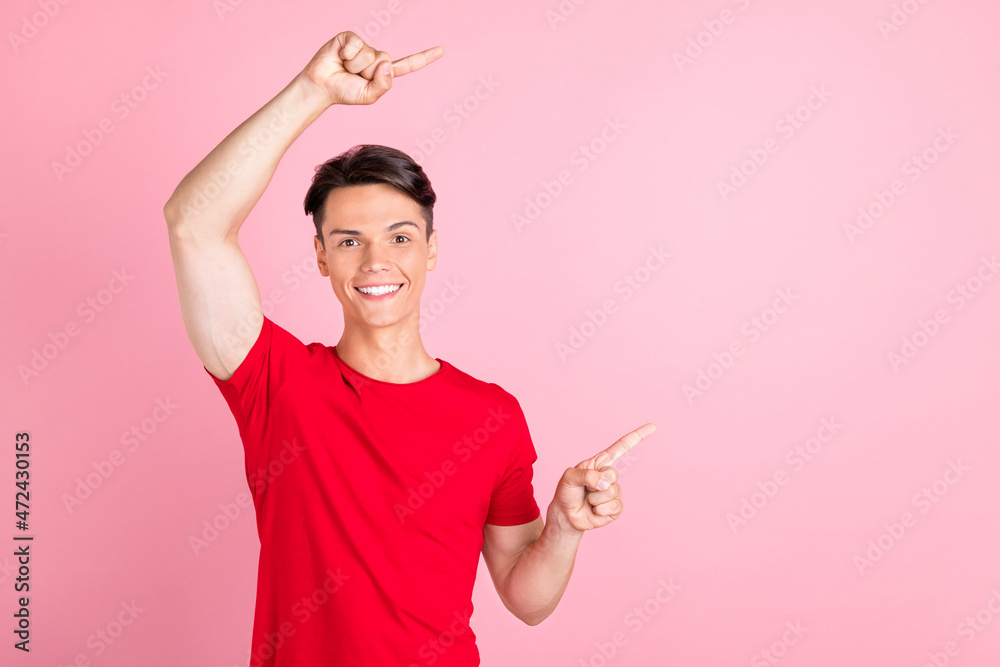 Photo of pretty sweet young man wear red t-shirt smiling pointing fingers empty space isolated pink color background Photo of pretty sweet young man wear red t-shirt smiling pointing fingers empty space isolated pink color background