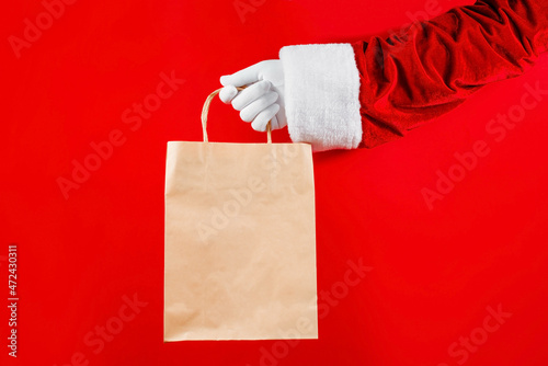 Trendy craft package in Santa's hands on a red background. Sale, contactless, holidays concept.