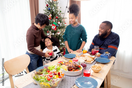 Happy family with mother giving gift box with daughter during dinner at home  celebration in xmas with parent surprising children with enjoyment at house  thanksgiving eve  Merry Christmas.