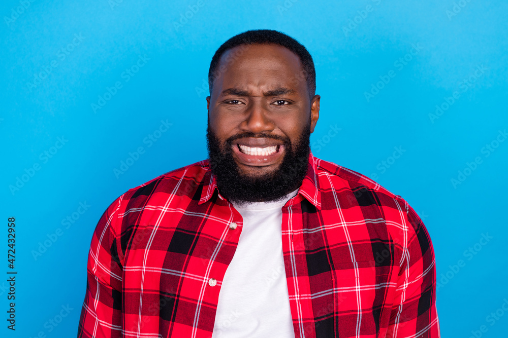 Photo of young unhappy upset sad man wear plaid red shirt bad mood isolated on blue color background Photo of young unhappy upset sad man wear plaid red shirt bad mood isolated on blue color background