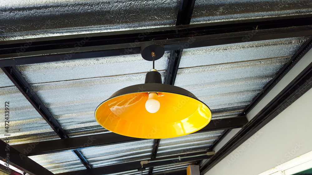 Yellow lamp hanging from the metal roof in a house