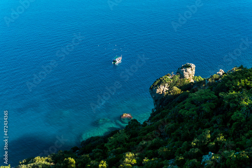 small tourist boat in the sea near rocky shore, aerial view