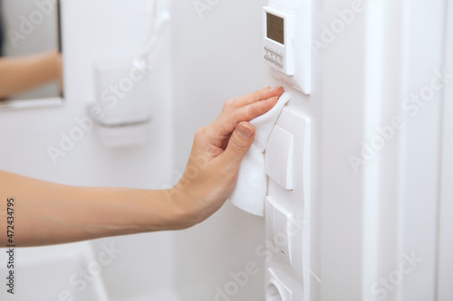 Cleaning switches and sockets with a microfiber cloth. Woman hand using wet wipe for cleaning home room door link. Sanitize surfaces prevention in hospital and public spaces against corona virus