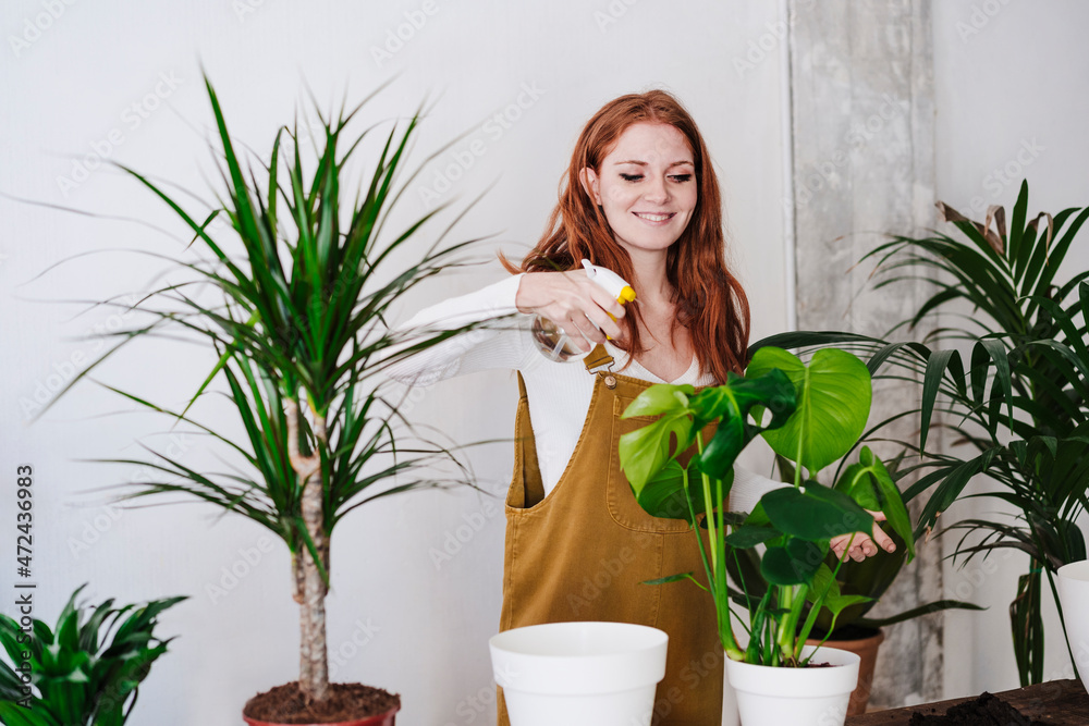 Woman spraying water on plants at home