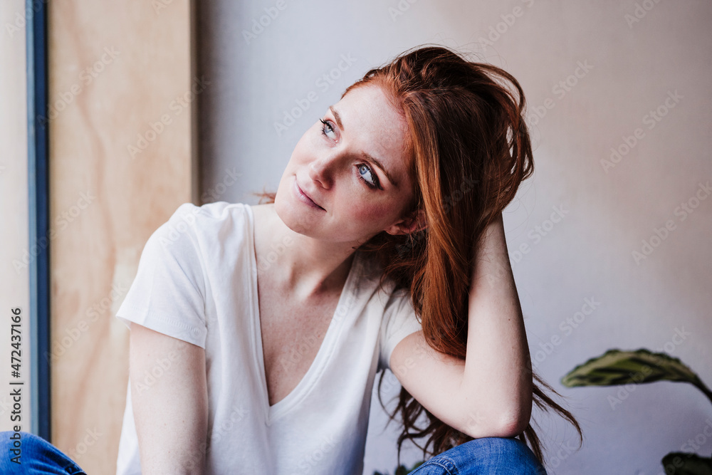 Woman with hand in hair day dreaming at home Woman with hand in hair day dreaming at home