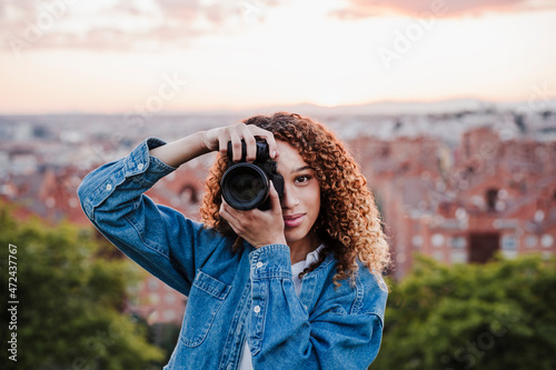 Smiling female photographer taking picture in park