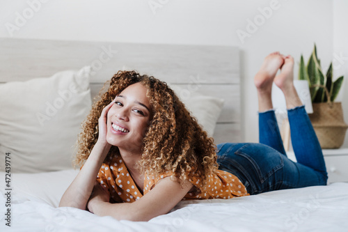 Young woman with head in hand lying on bed at home photo