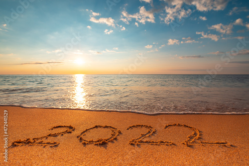 Fototapeta Naklejka Na Ścianę i Meble -  Happy New Year 2022 concept, lettering on the beach. Written text on the sea beach at sunrise.