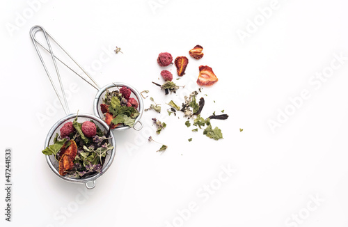 Dried tea leaves and berries in tea strainer. Composition with organic, natural herbal tea and dry berry on white desk. photo