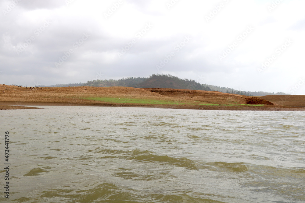 landscape view of river bank with dry land and hill on background from boat