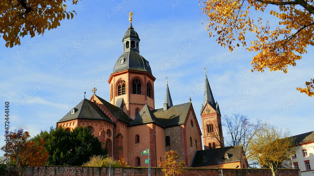 gewaltige Türme der Basilika in Seligenstadt malerisch zwischen  buntem Herbstlaub unter blauem Himmel