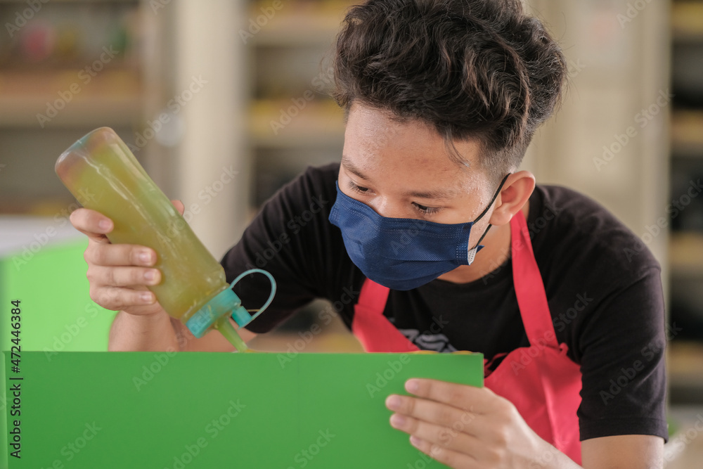 Young carpenters use contact glue in installing laminate for built-in cabinets at the workshop. Young carpenters use contact glue in installing laminate for built-in cabinets at the workshop.